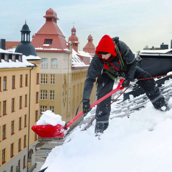 En snöskottare som skottar snö från ett tak