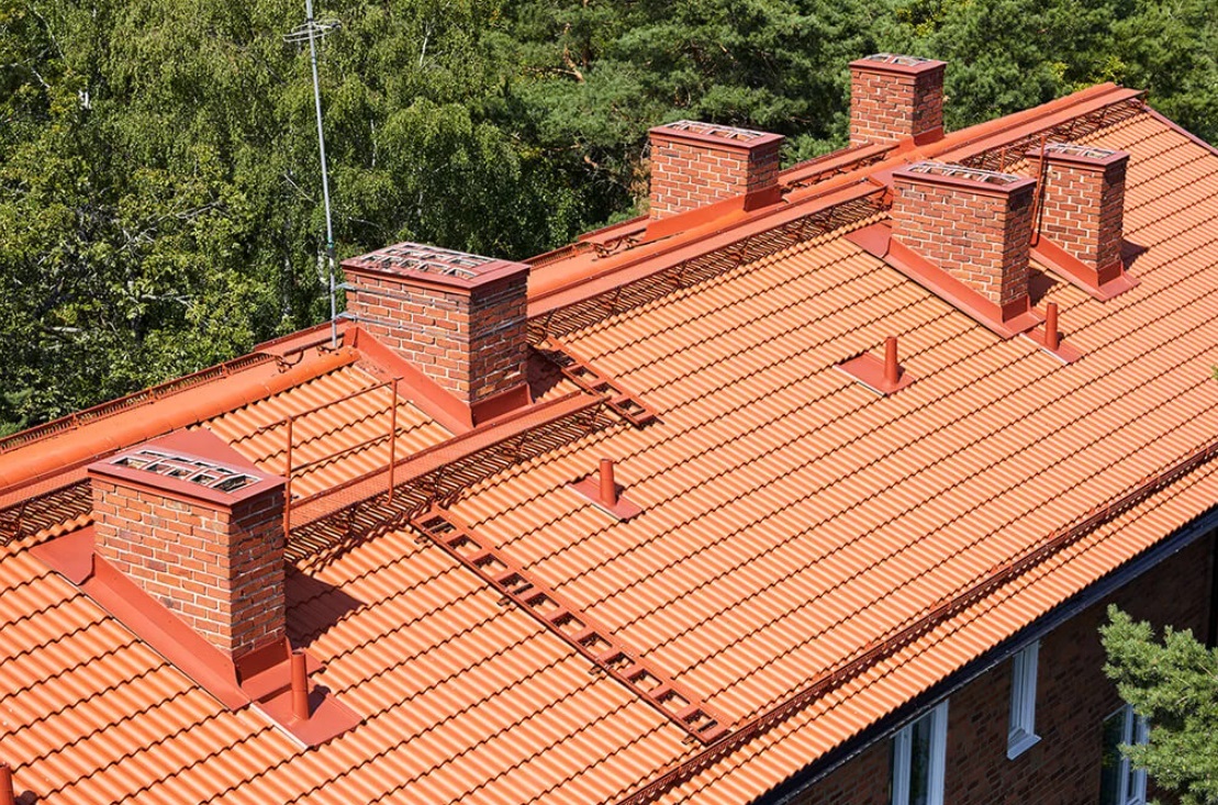 Takläggning i Bromma som gjorts på ett hus som fått röda takpannor och taksäkerhetsdetaljer.